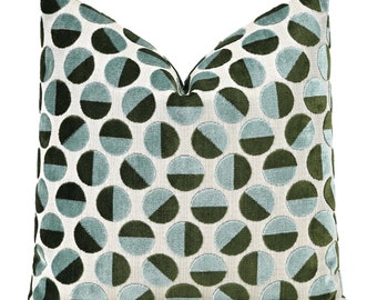 May include: Decorative throw pillow with a geometric pattern. The pillow features a repeating design of half-circles in shades of teal, dark green, and off-white. The pillow is square-shaped and has a soft, textured appearance.