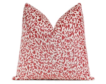 May include: A decorative cushion with a red and white abstract pattern. The cushion has a textured appearance and a soft look. The design features a repeating pattern of red shapes against a white background, creating a visually appealing accent piece for a sofa or bed.