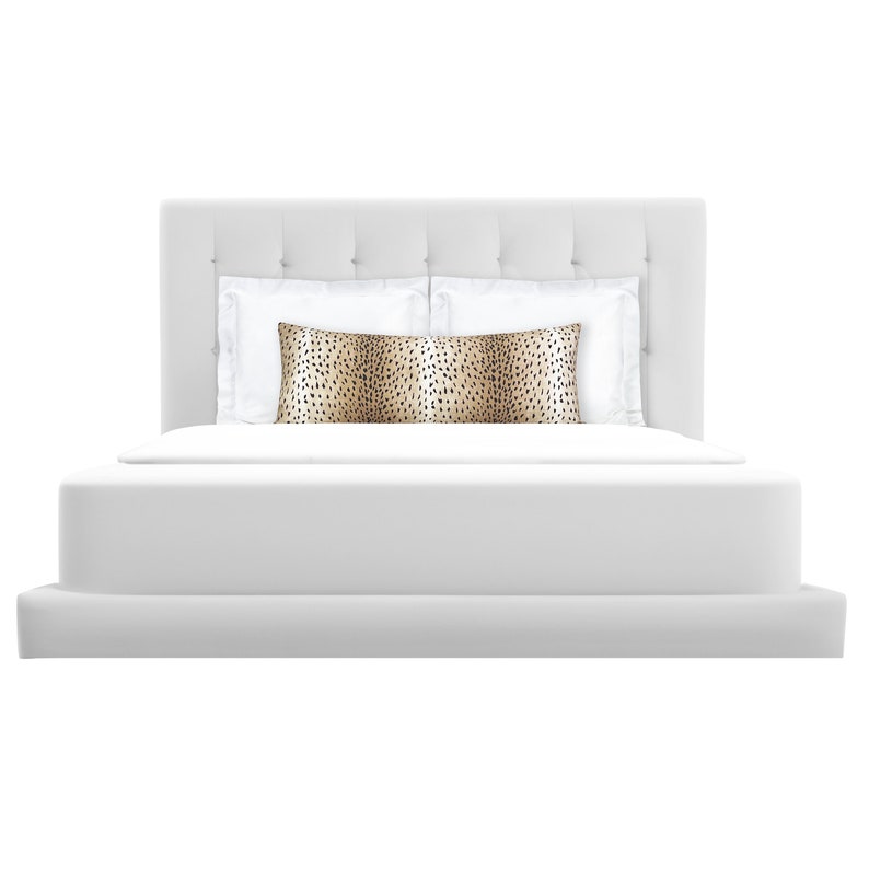 May include: A white upholstered bed with a tufted headboard and a white duvet. A brown and black patterned pillow is on top of the white pillows.