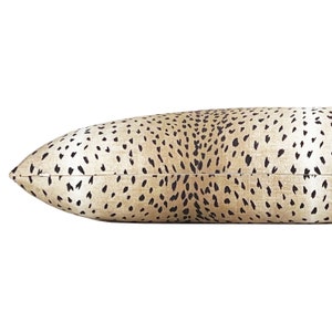 May include: A long, rectangular pillow with a beige background and a black cheetah print pattern.