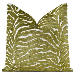 May include: A square throw pillow featuring a textured, raised olive green velvet pattern against a white background. The design consists of organic, flowing zebra-like stripes that cover the entire front surface of the pillow cover.