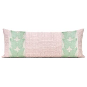 May include: A long, rectangular decorative pillow with a light pink woven fabric. The ends feature a vertical panel with three light green butterfly appliqués. The pillow is designed for a bed or sofa and adds a touch of nature-inspired decor.