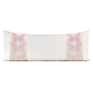 May include: A rectangular white decorative pillow with pink butterfly embroidery on each end. The butterflies are arranged in vertical rows of three. The pillow has a textured surface and a soft, inviting appearance.