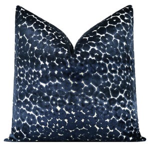 May include: A square decorative pillow with a navy blue leopard print pattern. The pillow has a soft, velvety texture and a white background. The pillow is designed for home decor.