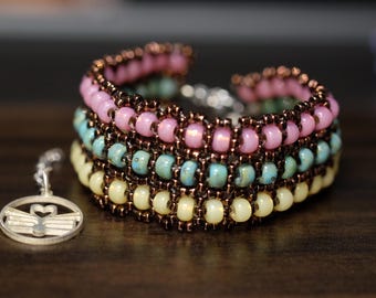 May include: A multi-layered beaded bracelet with pink, turquoise, and cream colored beads. The bracelet is made with small seed beads and has a delicate, feminine look.