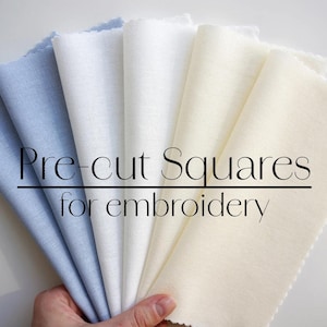May include: A collection of pre-cut fabric squares in white and light blue, perfect for embroidery projects. The squares are arranged in a fan shape, with the text "Pre-cut Squares for embroidery" printed on top.