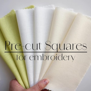 May include: Pre-cut squares of fabric in green, white, and cream colors, perfect for embroidery projects. The fabric squares are arranged in a fan shape.