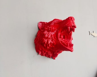 May include: A red 3D printed sculpture of a bear's head with its mouth open in a roar. The sculpture is mounted on a wall.
