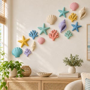 Pode incluir: Uma coleção de peças decorativas de parede com várias formas de vida marinha, incluindo estrelas-do-mar, conchas e ramos de coral em tons pastel de rosa, amarelo, azul, turquesa e roxo dispostos num padrão diagonal numa parede lisa.