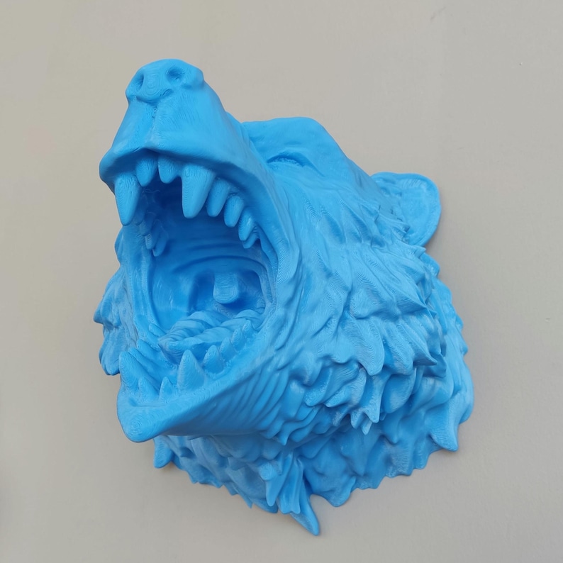 May include: A 3D printed blue wolf head sculpture with an open mouth and sharp teeth. The sculpture is made of a textured material and has a realistic appearance.