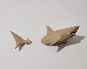 May include: Two origami paper sharks, one large and one small, are made of brown paper and are displayed on a white surface.