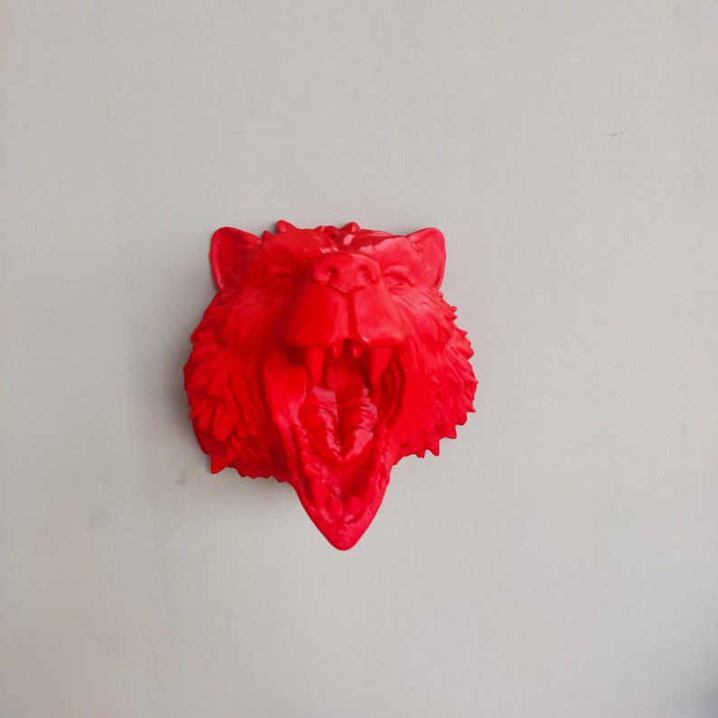 May include: A red 3D printed animal head sculpture of a snarling wolf or fox with a wide open mouth. The sculpture is made of a smooth, solid red plastic.