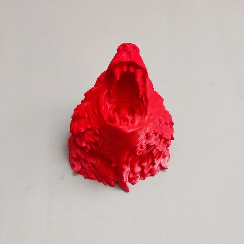 May include: A 3D printed red sculpture of a snarling creature with a large open mouth and sharp teeth.