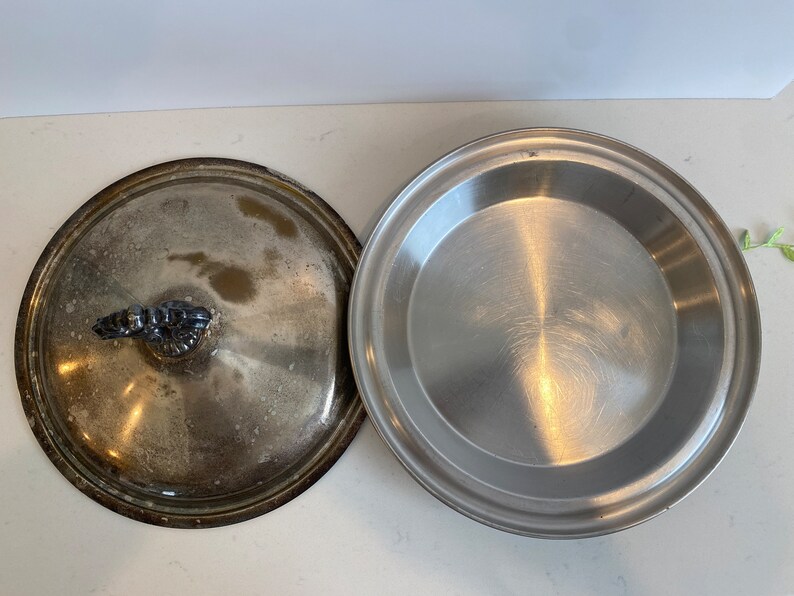 Puede incluir: Un plato para tartas de plata con un asa decorativa y un molde para tartas de plata.