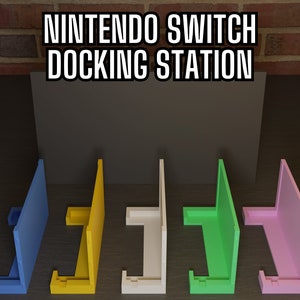 May include: Five Nintendo Switch docking stations in different colors: blue, yellow, white, green, and pink. The docking stations are all the same design, with a slot for the Switch console and a stand for the Joy-Cons.