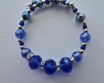 May include: A blue beaded bracelet with a mix of round and faceted beads. The bracelet features a variety of blue shades, including deep sapphire and lighter hues. Silver-colored spacer beads and rhinestone accents add sparkle.