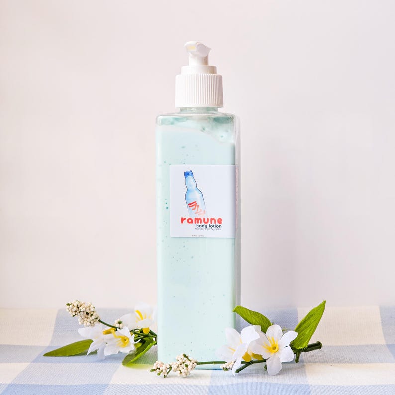 Pode incluir: Uma garrafa de pl&aacute;stico transparente de lo&ccedil;&atilde;o corporal com uma tampa de bomba branca. A garrafa tem um r&oacute;tulo azul e vermelho com o texto "ramune body lotion".