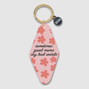 May include: Pink keychain with a floral pattern and the phrase "sometimes good moms say bad words." The keychain has a gold ring and a small black tag that says "Properly Improper."