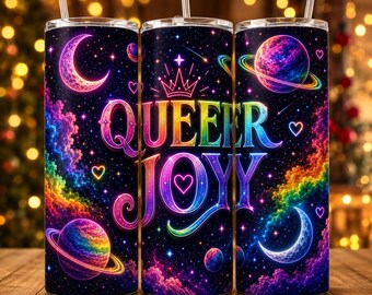 May include: A cylindrical tumbler with a straw featuring a dark space-themed design with colorful nebulae, planets, moons, and hearts. The text QUEER JOY is printed in a vibrant rainbow gradient font, accented by a crown icon above the lettering.