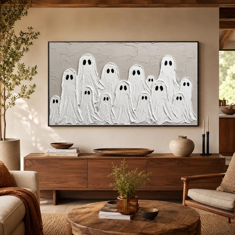 May include: A rectangular wall art piece featuring a textured light gray background with a group of white ghost figures painted in a thick impasto style. Each ghost has two simple black oval eyes. The artwork is enclosed in a thin black frame.