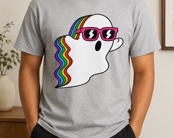 May include: A heather gray short-sleeved t-shirt featuring a central graphic of a white ghost wearing bright pink sunglasses. The ghost has a flowing rainbow-colored trail extending from its head down its back, rendered in vibrant stripes.
