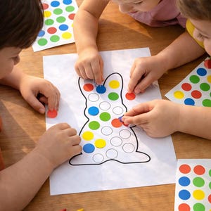 Könnte beinhalten: Kinderaktivität mit einer weißen Papier-Hasen-Umrisslinie und farbigen Punktaufklebern. Kinder platzieren die Aufkleber auf der Hasenform. Buntstifte in Rot, Gelb und Blau liegen auf dem Tisch. Pädagogische und kreative Aktivität.