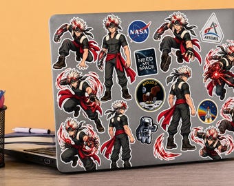 May include: A grey laptop covered in various stickers, including multiple anime-style character decals with spiky white hair, black outfits, and red accents, alongside NASA, Artemis, Apollo 11, and I Need My Space themed circular and square stickers.