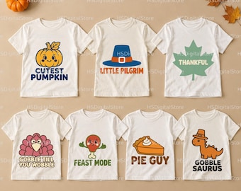 Puede incluir: Siete camisetas blancas de manga corta con gráficos y texto temáticos de Acción de Gracias. Los diseños incluyen una calabaza con 'CUTEST PUMPKIN', un sombrero de peregrino con 'LITTLE PILGRIM', una hoja con 'THANKFUL', un pavo con 'GOBBLE TILL YOU WOBBLE', un muslo de pollo con 'FEAST MODE', un trozo de tarta con 'PIE GUY' y un dinosaurio con 'GOBBLE SAURUS'.
