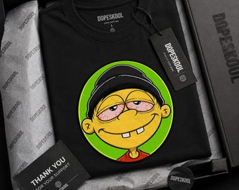 May include: A black t-shirt featuring a circular graphic of a yellow cartoon character with a black beanie, bloodshot eyes, and two front teeth. The shirt includes a black hang tag with the text DOPESKOOL and a thank you card in a black box.