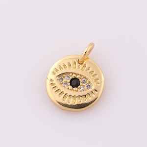 May include: Gold charm with a black and white evil eye design. The eye is surrounded by small white stones.
