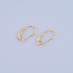 May include: Two gold-toned earring hooks with a curved design. The hooks are made of metal and have a smooth finish.
