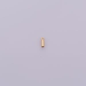 May include: A small, gold-colored jewelry finding, a crimp tube, is shown against a light purple background. The tube is cylindrical with a small loop at the top. This jewelry component is used for stringing beads and securing clasps.
