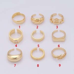 Könnte beinhalten: Neun goldfarbene Ringe mit verschiedenen Designs. Die Ringe sind in drei Reihen zu je drei angeordnet. Die Ringe sind alle offen und haben ein schlichtes Design.