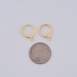 Puede incluir: Dos pendientes de aro de oro con cierre de bisagra. Los pendientes se muestran junto a una moneda de diez centavos de d&oacute;lar estadounidense para comparar el tama&ntilde;o.
