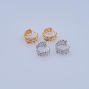 May include: Two pairs of hoop earrings with a leaf design. One pair is gold and the other is silver.