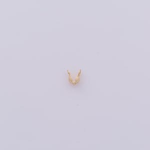 Peut inclure: Un petit &eacute;l&eacute;ment de bijouterie dor&eacute;, possiblement un fermoir ou un connecteur, est centr&eacute; sur un fond blanc uni. La pi&egrave;ce a une forme en V avec deux extr&eacute;mit&eacute;s arrondies, sugg&eacute;rant qu'elle est con&ccedil;ue pour maintenir quelque chose.