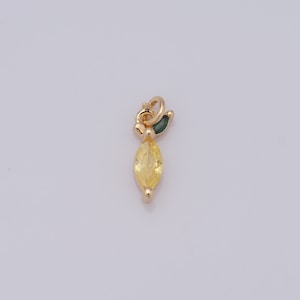 Op de afbeelding: Een gouden bedel met een gele, markiesvormige edelsteen en een groen bladdetail.