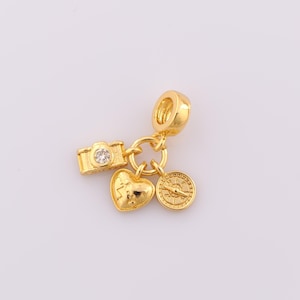 May include: Gold charm with a heart, compass, and camera design. The camera has a small clear rhinestone.