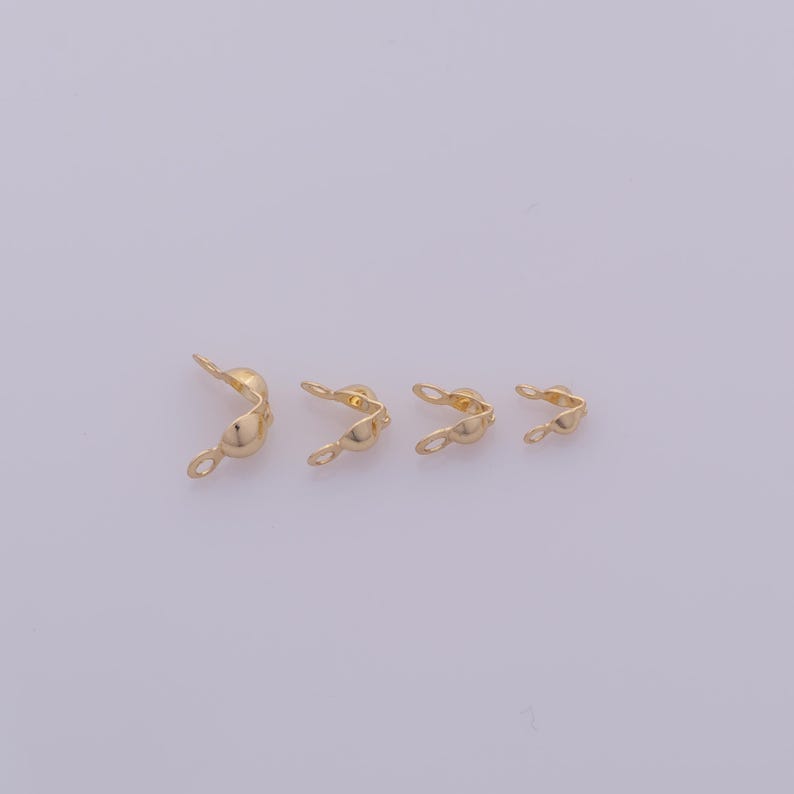 Peut inclure: Quatre embouts de sertissage dor&eacute;s, utilis&eacute;s en bijouterie. Chaque embout a une forme incurv&eacute;e avec une boucle &agrave; une extr&eacute;mit&eacute; et un sertissage &agrave; l'autre. Les embouts sont dispos&eacute;s du plus grand au plus petit.