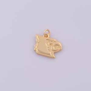 Puede incluir: Un dije de metal en tono dorado con forma de perfil de cabeza de ave cardenal. El dije presenta un diseño en relieve del ave con un pico y un ojo definidos, e incluye una pequeña argolla circular unida en la parte superior para colgar.