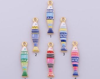 May include: Six metal fish-shaped charms with enamel detailing in various colors including blue, yellow, green, red, and pink. Each charm features a small loop at the top for hanging and is numbered one through six in black text below each piece.