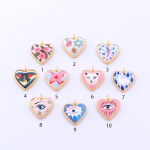 Puede incluir: Una colección de diez colgantes en forma de corazón con bordes dorados. Cada colgante presenta un diseño único, que incluye patrones florales, una mariposa, una cara de gato, un ojo y una luna creciente. Los colgantes son de varios colores.