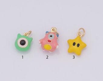 May include: Three gold charms with enamel paint. The first charm is green and shaped like a monster with one eye. The second charm is pink and shaped like a monster with one eye. The third charm is yellow and shaped like a star with two eyes.