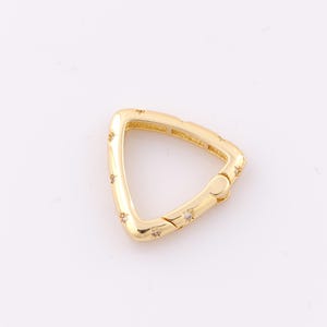 May include: Gold-toned triangle-shaped clasp with small clear rhinestones around the edge.
