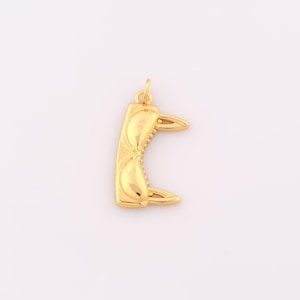 May include: A gold-colored charm in the shape of a pair of sunglasses. The charm is detailed with a textured surface and a loop for attaching to a necklace or bracelet.