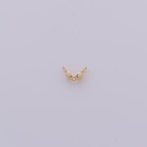 Peut inclure: Un petit charme dor&eacute; en forme de soutien-gorge. Le charme a deux bonnets et de petites boucles de chaque c&ocirc;t&eacute; pour l'attacher &agrave; une cha&icirc;ne ou un bracelet. Le charme est centr&eacute; sur un fond violet clair.