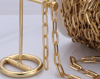 May include: A gold chain with oval links, displayed on a gold stand. The chain is also shown wound around a spool.