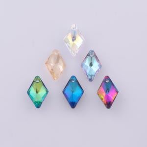 May include: A collection of six diamond-shaped crystal beads in various colors, including clear, peach, teal, blue, and iridescent. Each bead has a hole at the top for stringing. The crystals are arranged on a light background.
