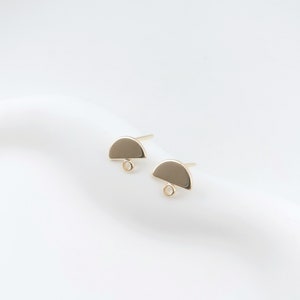 May include: A pair of gold-toned half-circle earring posts with a small loop at the bottom of each.