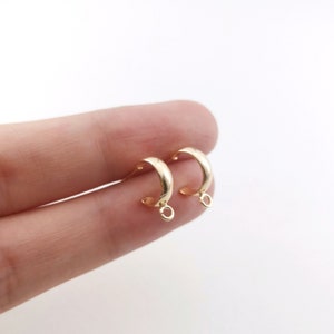 May include: A pair of gold-toned hoop earring findings with a jump ring attached to each hoop.